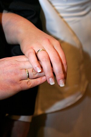 zwei Hänge mit Trauringen über einem Brautstrauß